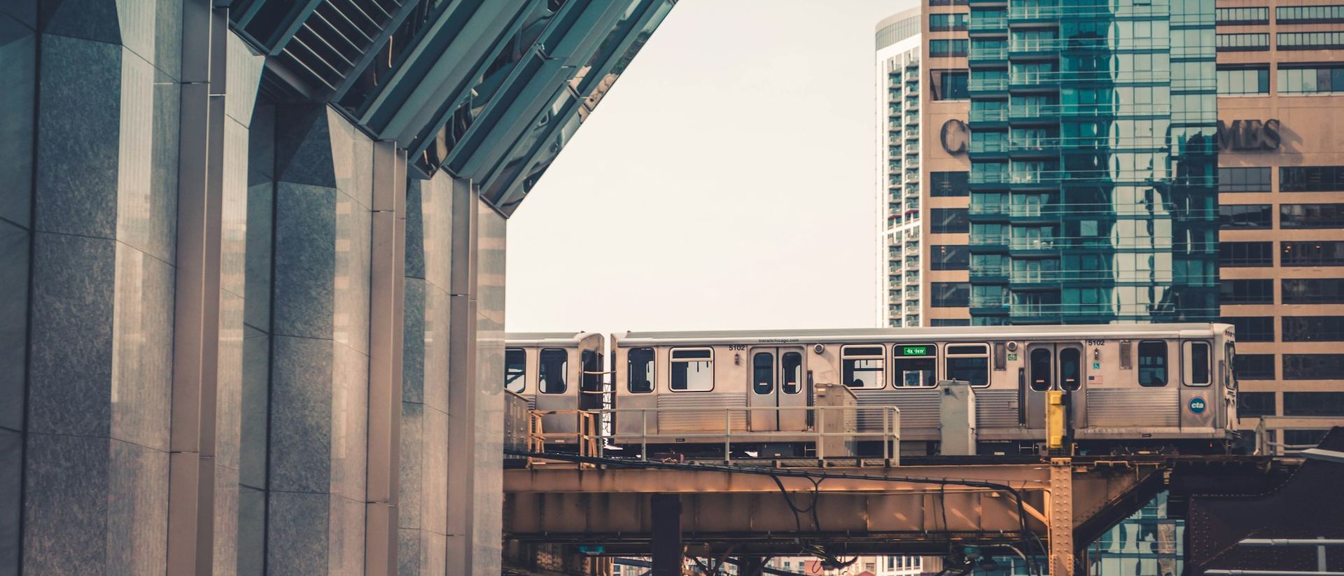 A Chicago L train passing between glass towers