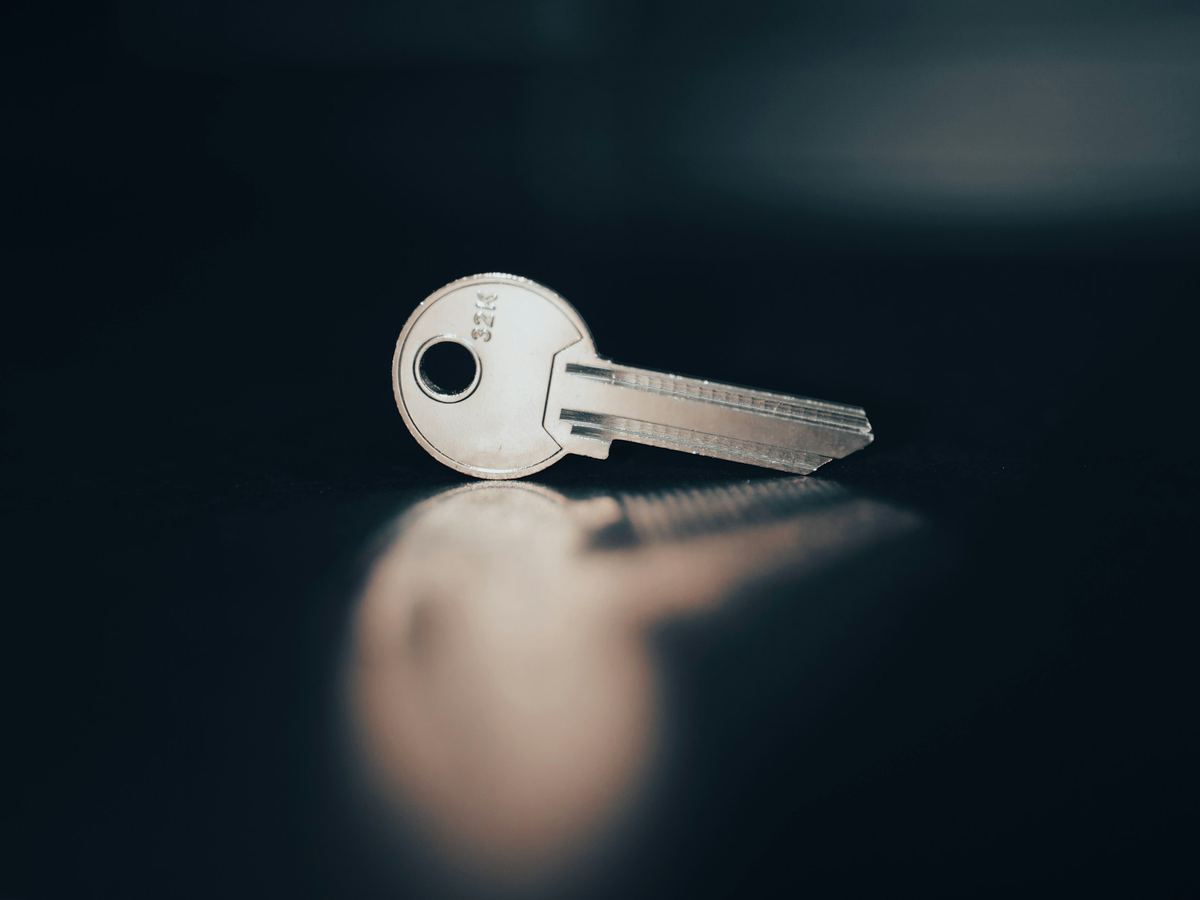 A single house key resting on a dark surface