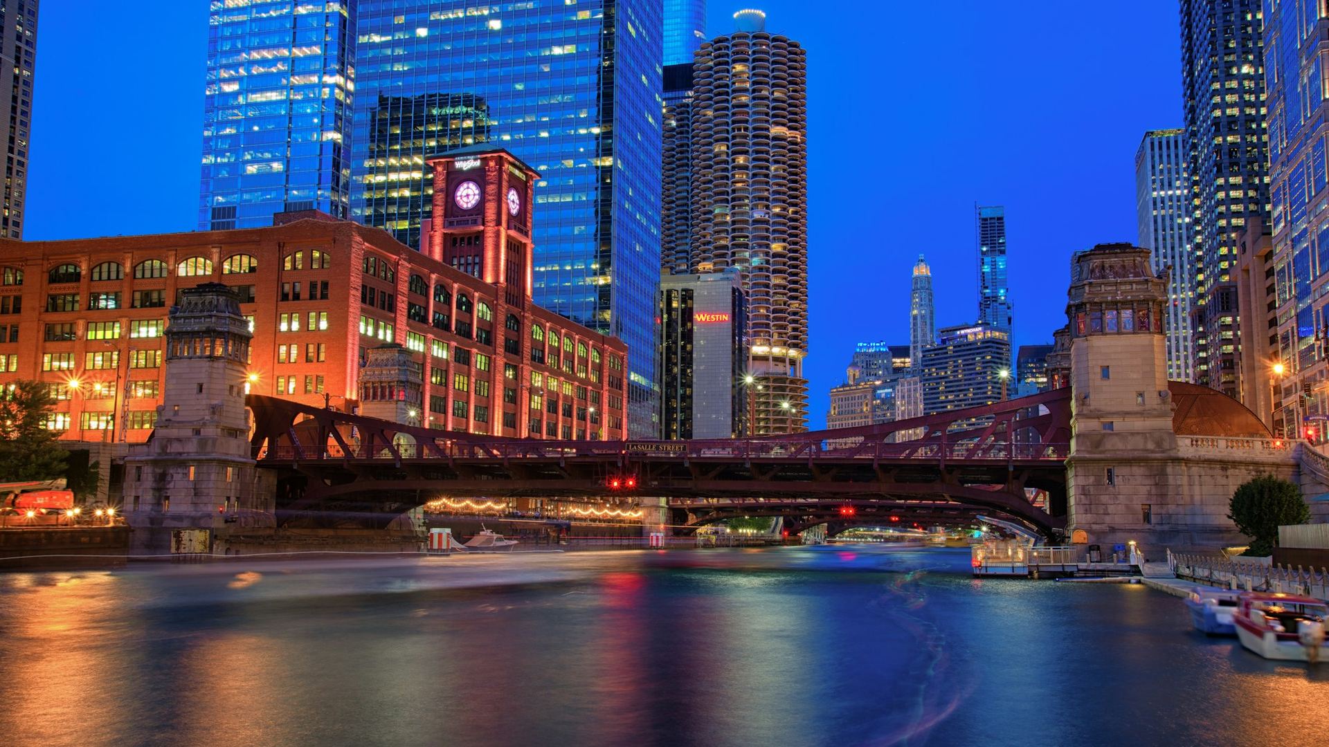 The Chicago River at dusk, lit bridges and towers reflected in the water